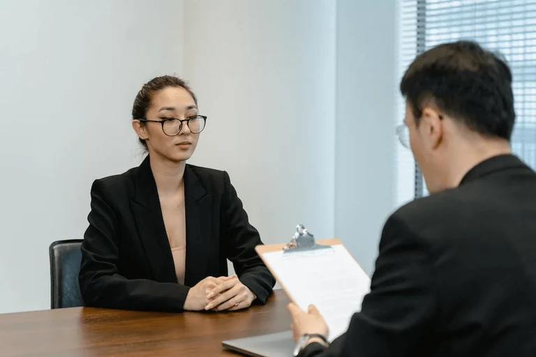 A man interviewing a potential female staff with a jotter on his desk