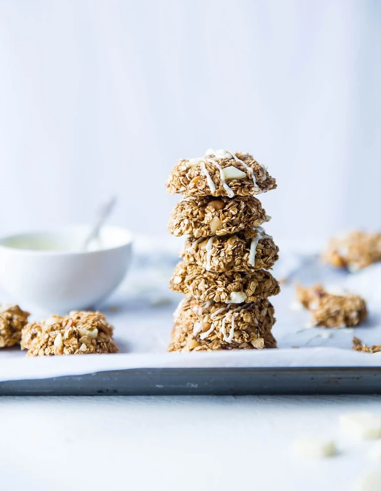 5 oatmeal/granola cookies with white icing rest on top of each other in a stack