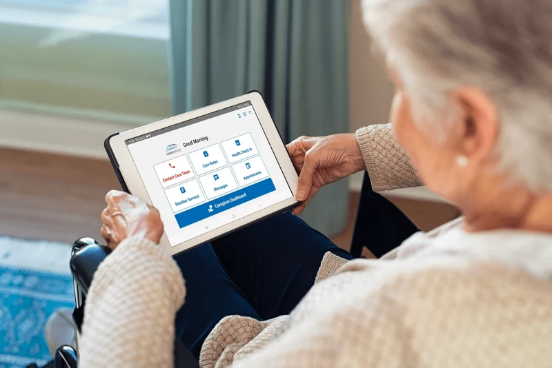 A person holding a tablet and using the CareBridge app. 