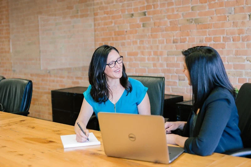Woman is interviewing for a Python developer job with another woman sitting near a laptop.