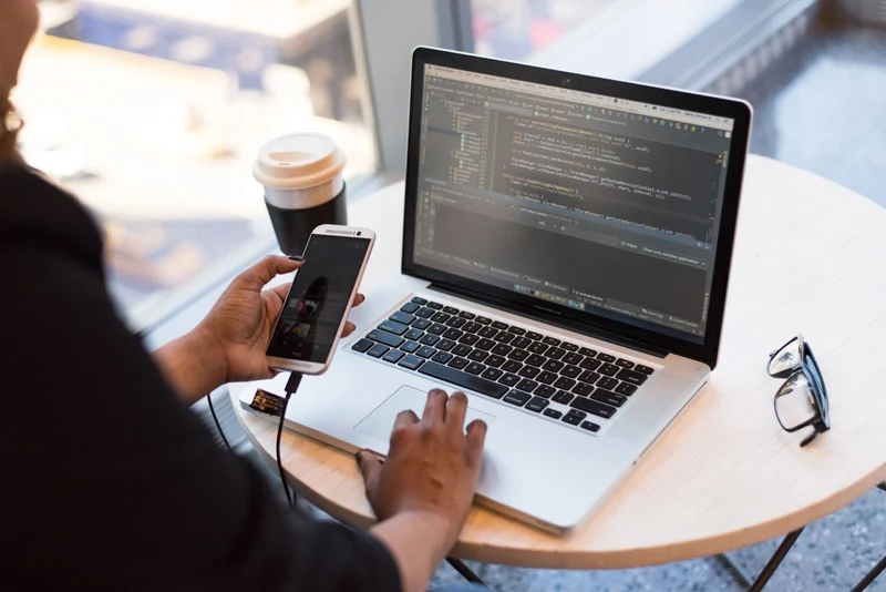 Developer running code from a laptop on a connected iOS mobile device being used for debugging