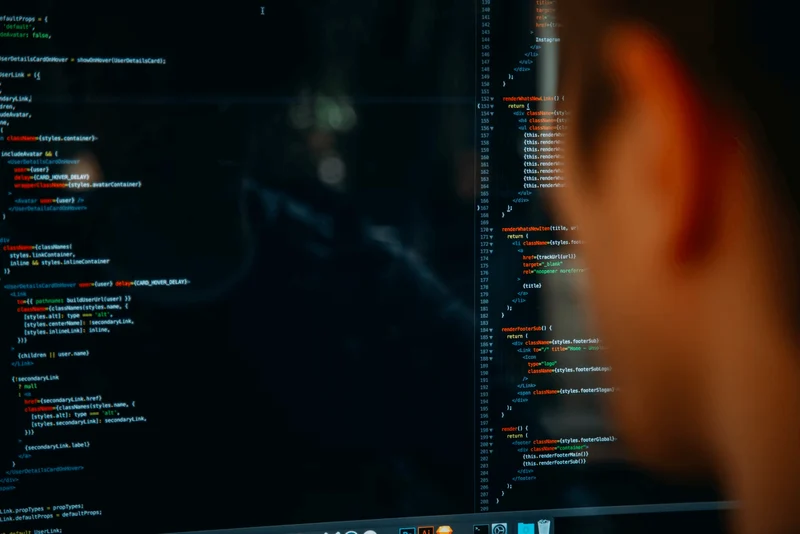 A person looking at a computer monitor that displays a programming language