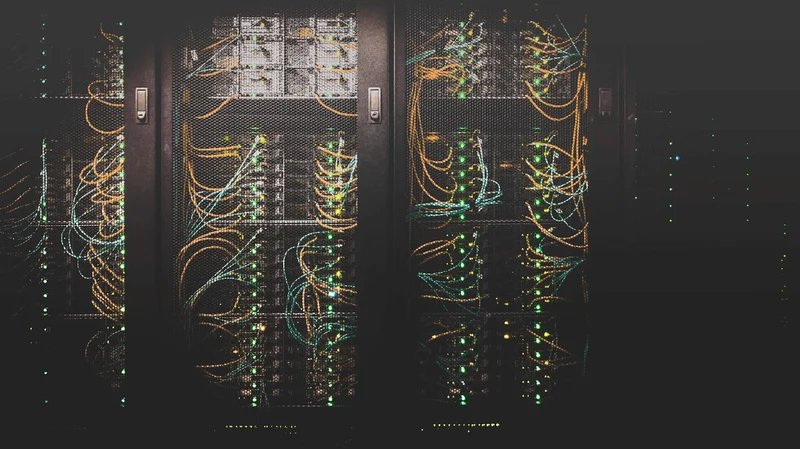 A photograph of a data center with multi-coloured wires protruding from multiple directions. 