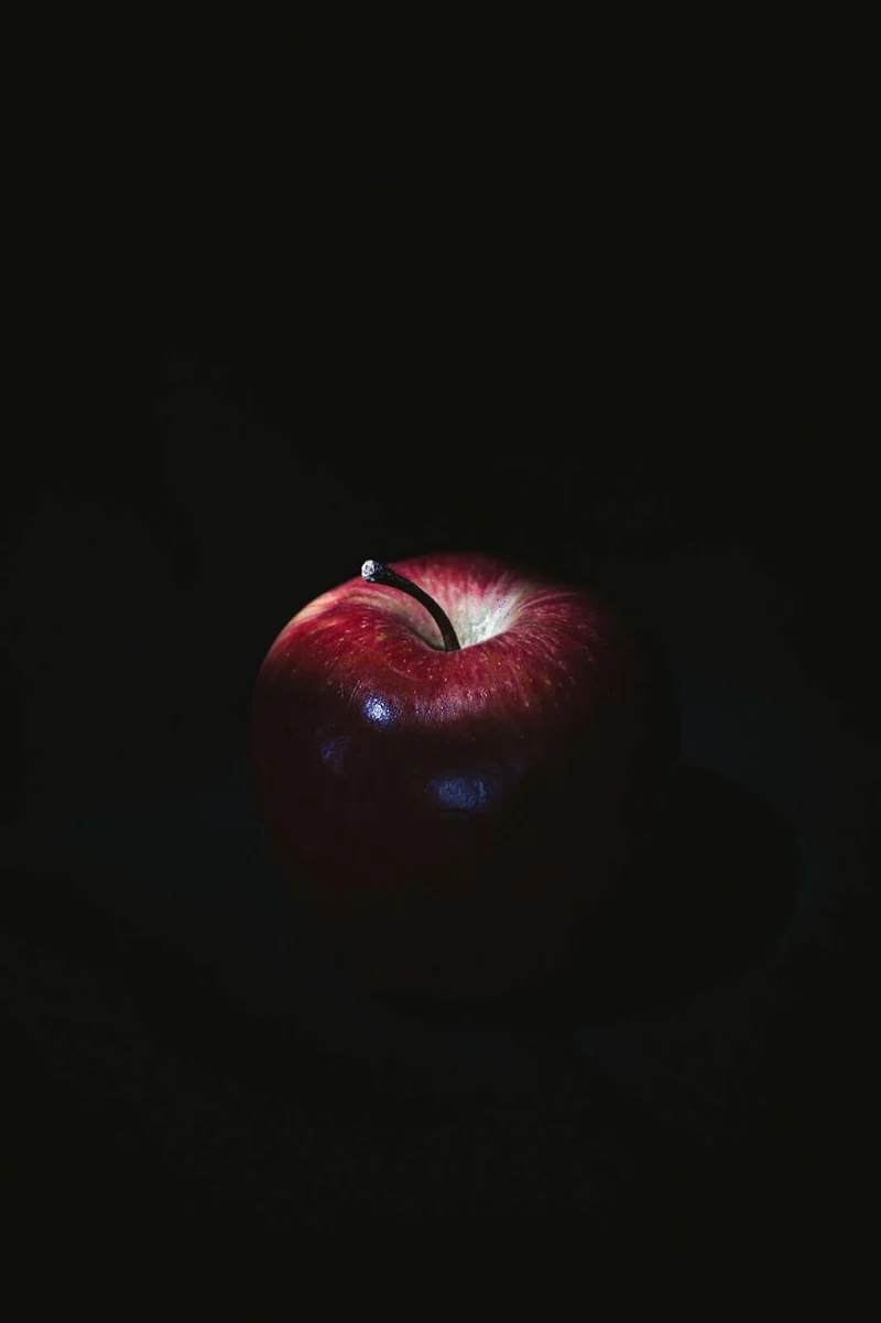 Outsourcing illustrated as a red apple enveloped in a sea of black, to demonstrate its darker side
