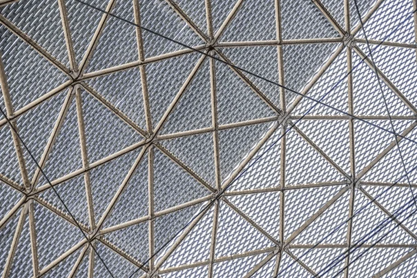 An iron lattice with crossed squares and interconnecting nodes, this image of a ceiling represents a web framework