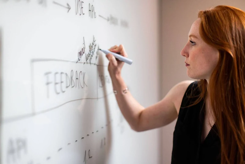 A female engineer is writing feedback on whiteboard.