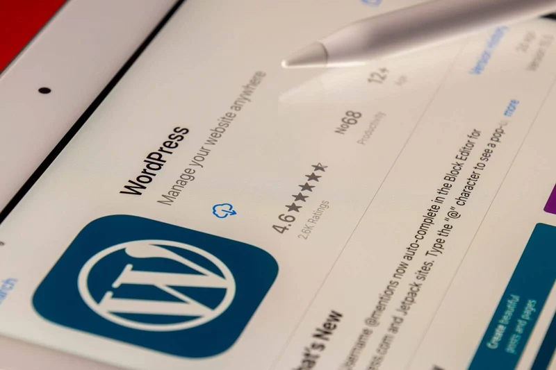 WordPress logo on a web page displayed on a white tablet with a stylus pen pointing at it. 