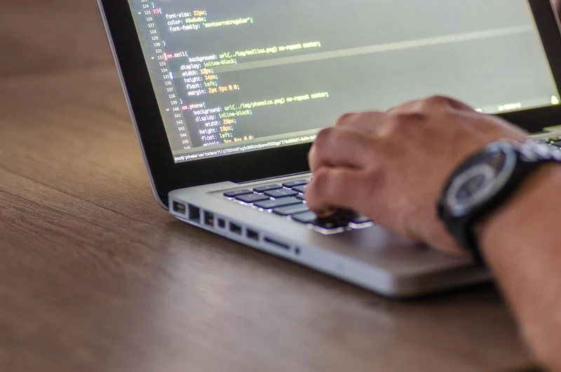 A web developer typing CSS code on a laptop. 